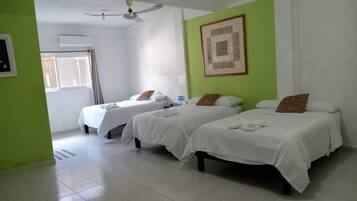 A hotel room with three beds, a ceiling fan, and a framed picture on the wall.