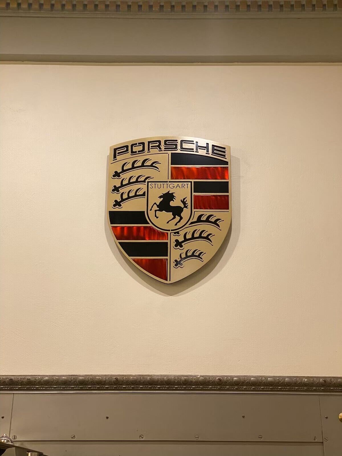 Logotipo de Porsche montado en la pared con el texto "STUTTGART" y un emblema de caballo.