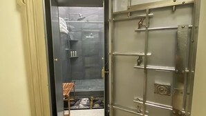 A room with a large safe, a shower, and a vanity with a mirror.