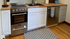 A modern kitchen with white cabinets, a stainless steel stove, and a dishwasher.