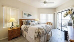 A bedroom with a bed, two bedside tables, a ceiling fan, and a view of the outside balcony. - Fountain Hills Golf Condo | Heated Pool & Hot Tub (Fountain Hills)