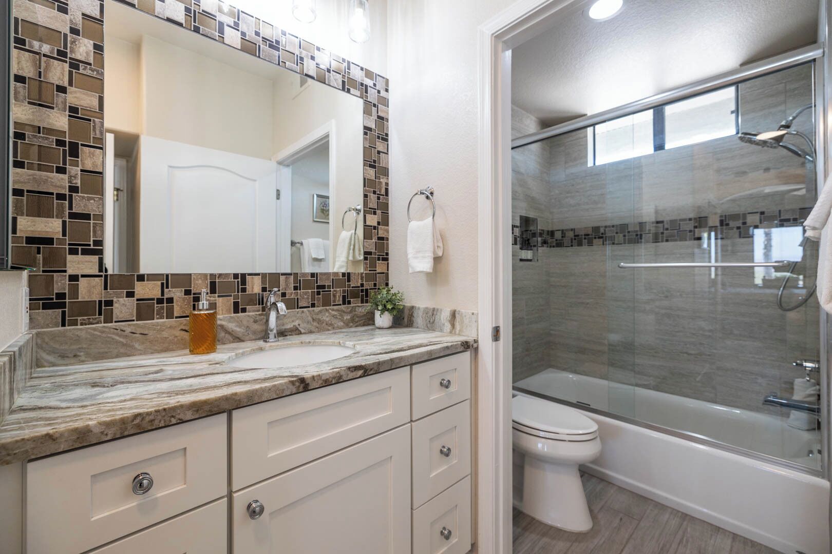 A modern bathroom with a marble sink, a glass shower enclosure, and a toilet.