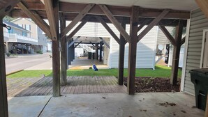 A covered porch with wooden beams, a concrete floor, and a view of a street and houses in the background. - Charming 3-bedroom house with WiFi, AC in marvelous Myrtle Beach (Myrtle Beach)