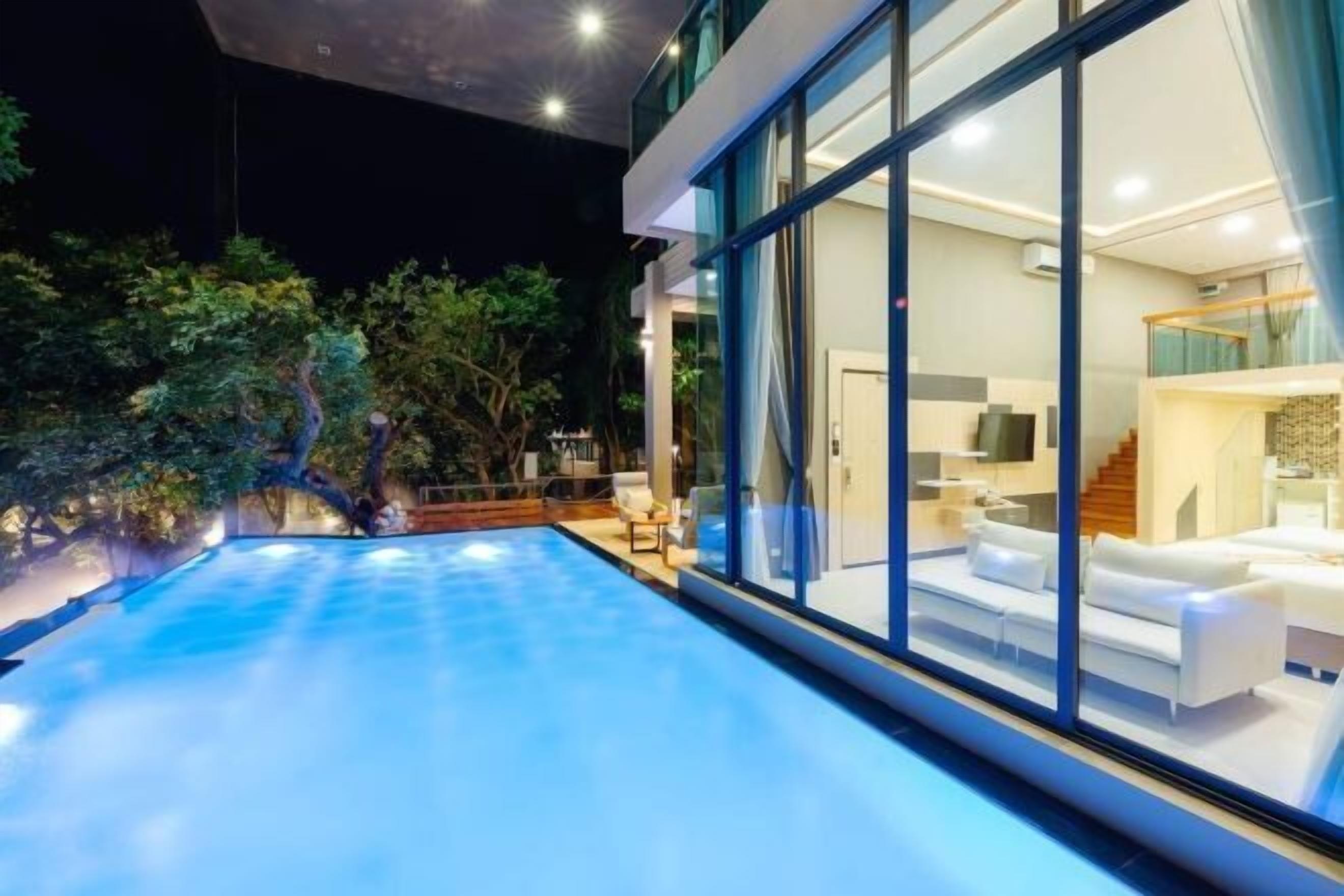A modern house with a swimming pool, large windows, and a well-lit interior.