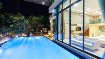 Una casa moderna amb piscina, finestres amples i interior ben il·luminat.