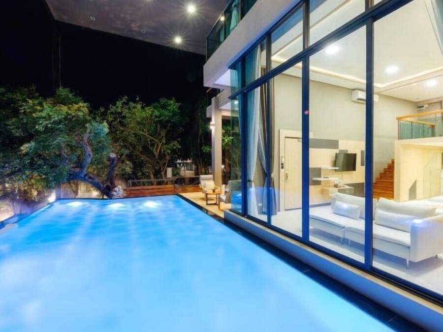 Una casa moderna amb piscina, finestres amples i interior ben il·luminat.