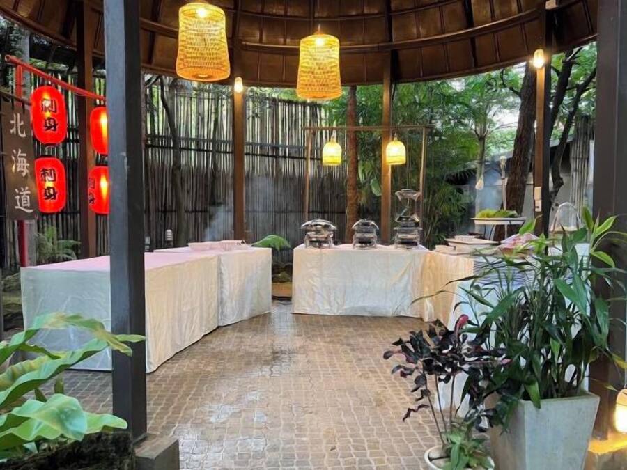 A covered outdoor dining area with tables, hanging lights, and red lanterns.