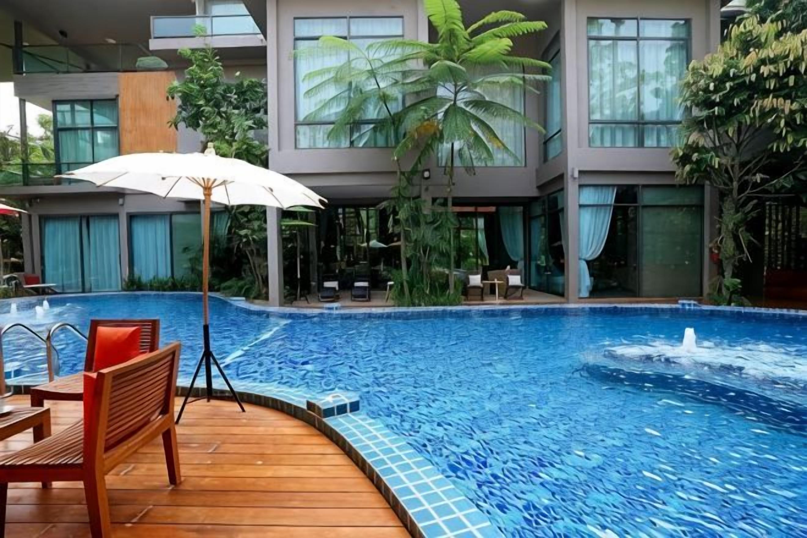 A swimming pool with a wooden deck, lounge chairs, and a table.