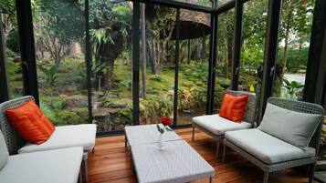 Un invernadero con asientos y vistas a un jardín.