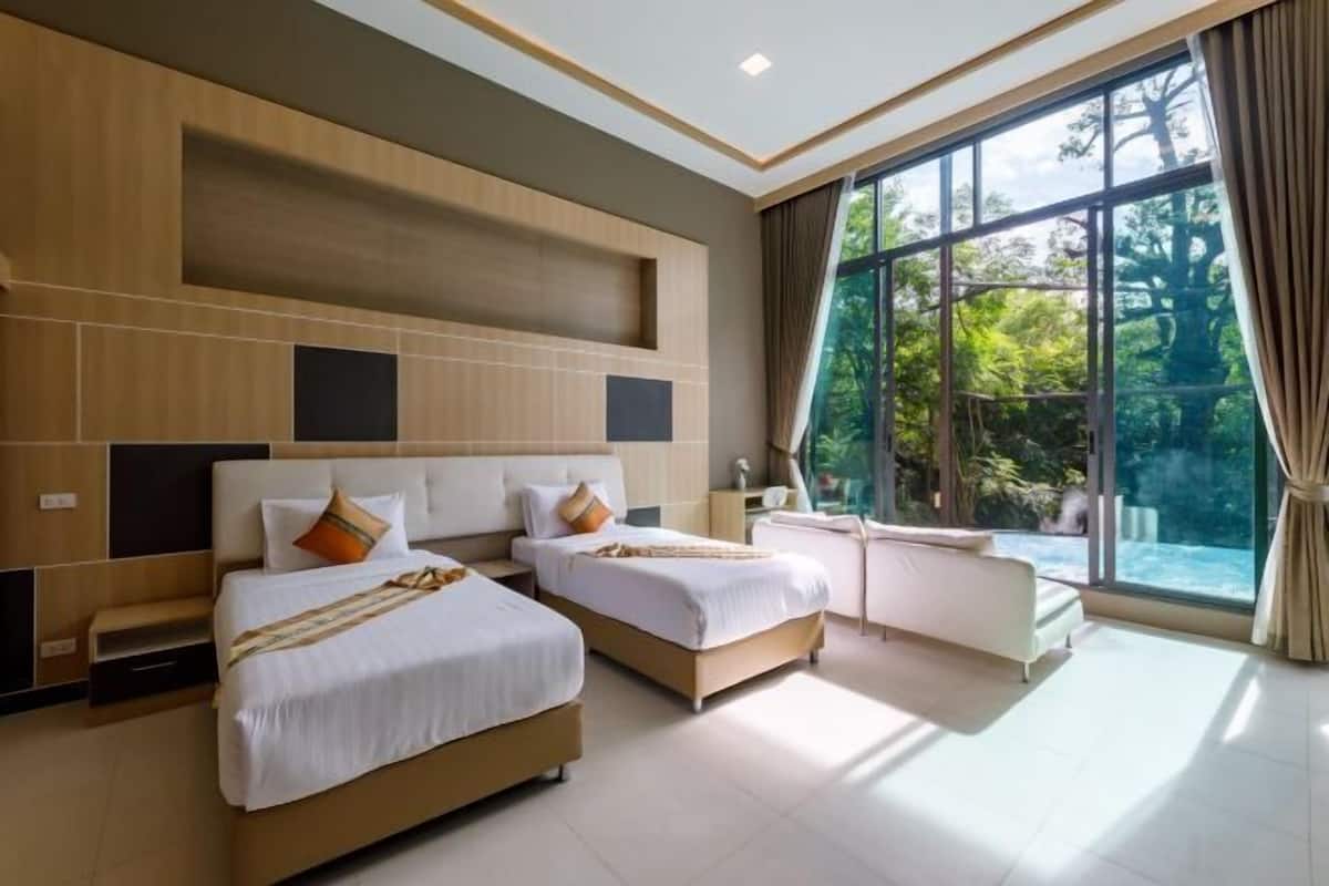 A modern hotel room with two beds, a sofa, a large window with a view of trees, and a built-in shelf.