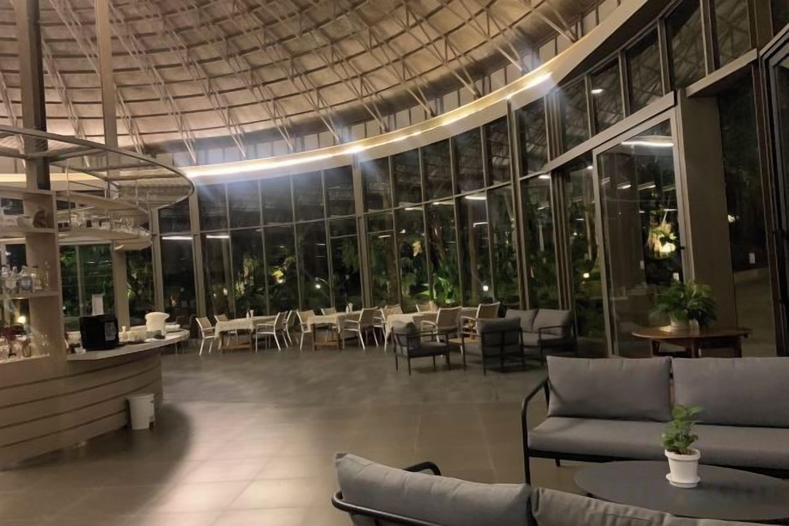 Un espacio interior amplio con techo curvo, ventanas grandes y arreglos de asientos.