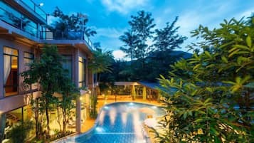 Un hotel modern amb piscina, zones d'estar a l'aire lliure i vegetació exuberanta.