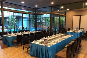 Un salón de conferencias con mesas largas, sillas y vistas a una piscina.