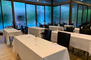 A conference room with tables and chairs, large windows, and a view of greenery outside. - TreeScape Resort Chiang Mai (Hang Dong)