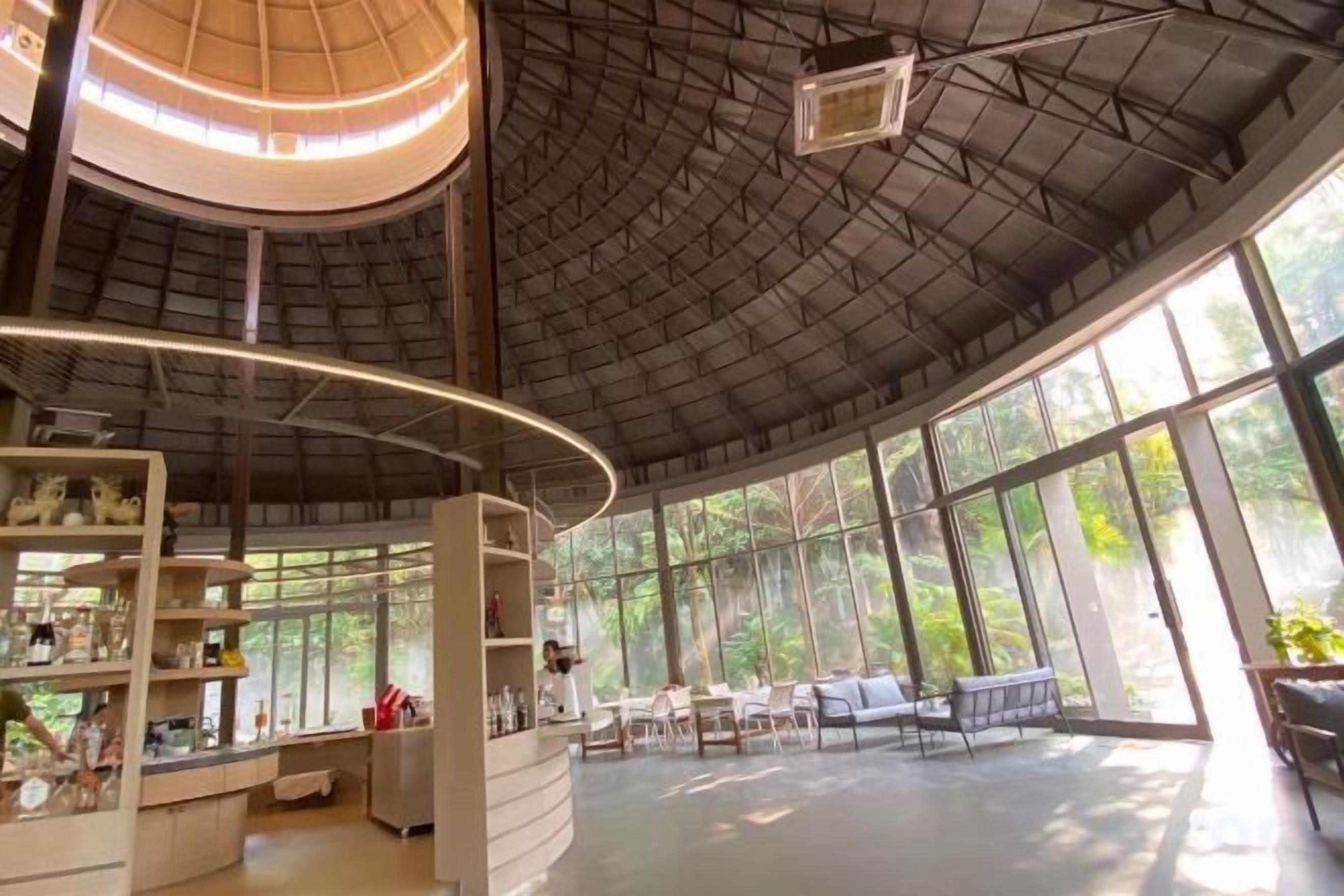 A spacious indoor area with a high ceiling, large windows, and a central seating area.