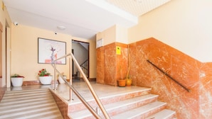 Eine Marmortreppe mit Handlauf, Topfpflanzen und einem gerahmten Bild an der Wand.