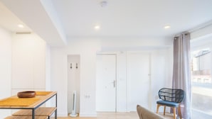 Ein modernes Interieur mit einem Esstisch, Stühlen, einem weißen Kleiderschrank und einem Fenster mit Vorhängen.