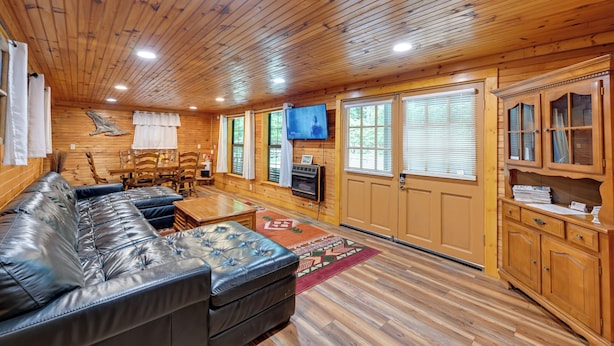 A wooden cabin interior with a leather sofa, dining table, chairs, a television, and wooden cabinets. - 6 Mi to Town: Robbinsville Apt w/ Deck & Grill (Robbinsville)