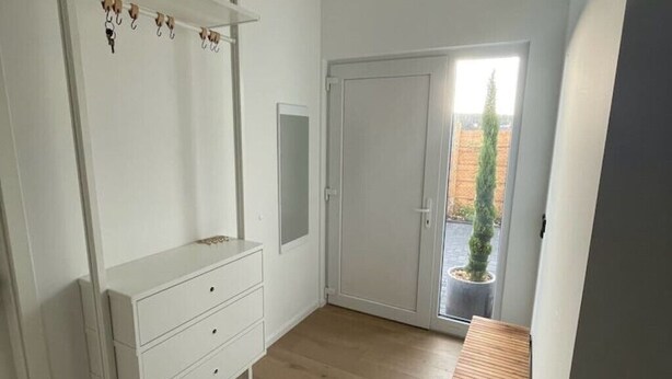 A room with a white dresser, a door leading to an outdoor area, and a small potted plant. - Privatunterkunft in Wendisch Rietz, Deutschland (Wendisch Rietz)