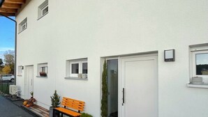A modern building with white exterior walls, multiple windows, and a door. There is a bench and potted plants outside. - Privatunterkunft in Wendisch Rietz, Deutschland (Wendisch Rietz)