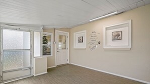A hallway with wooden flooring, white walls, and framed artwork.