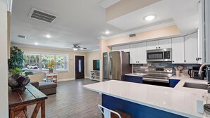 A modern kitchen with white cabinets, stainless steel appliances, and a large island.
