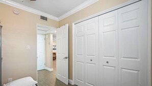 A hotel room with a bed, a white wardrobe, and a hallway leading to another room.