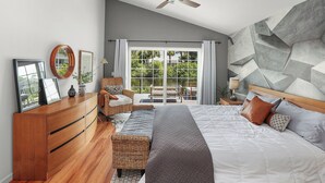 Un dormitorio con cama, cómoda, silla, ventilador de techo y vista al exterior a través de un ventanal.