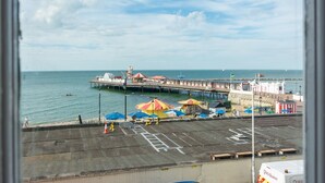 Eine Pier, die sich ins Wasser erstreckt, mit einem Parkplatz im Vordergrund.