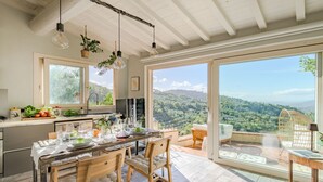 A spacious kitchen with a large island, wooden chairs, and a dining table set for six. - Panoramic Farmhouse with Pool and Amazing Views (Monsummano Terme)