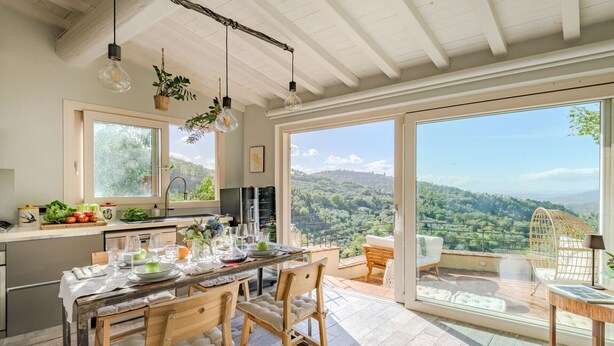 Une cuisine spacieuse avec un grand îlot central, des chaises en bois et une table à manger pour six personnes.