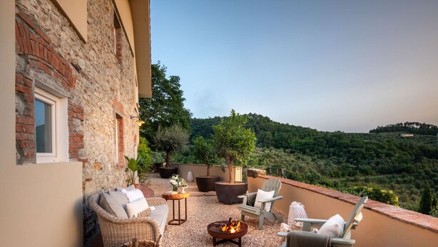 A terrace with wicker furniture, a fire pit, and potted plants. - Panoramic Farmhouse with Pool and Amazing Views (Monsummano Terme)
