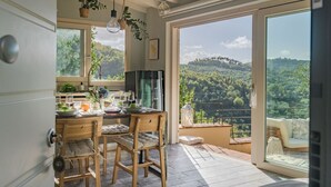 Une cuisine avec des chaises en bois, une table à manger et une vue sur un paysage montagneux, visible à travers de grandes fenêtres.