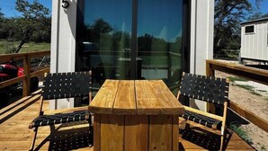 A modern two-story building with a deck featuring a wooden table and chairs. - Unit #5 - Modern Tiny Home in the heart of TX Wineries (Johnson City)