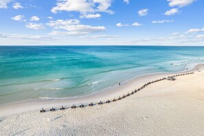 A beach with clear turquoise waters, a sandy shore, and a row of umbrellas. - HappyPlace30A-Gulf Views/Pool/Beach 3-Minute Walk (Santa Rosa Beach)