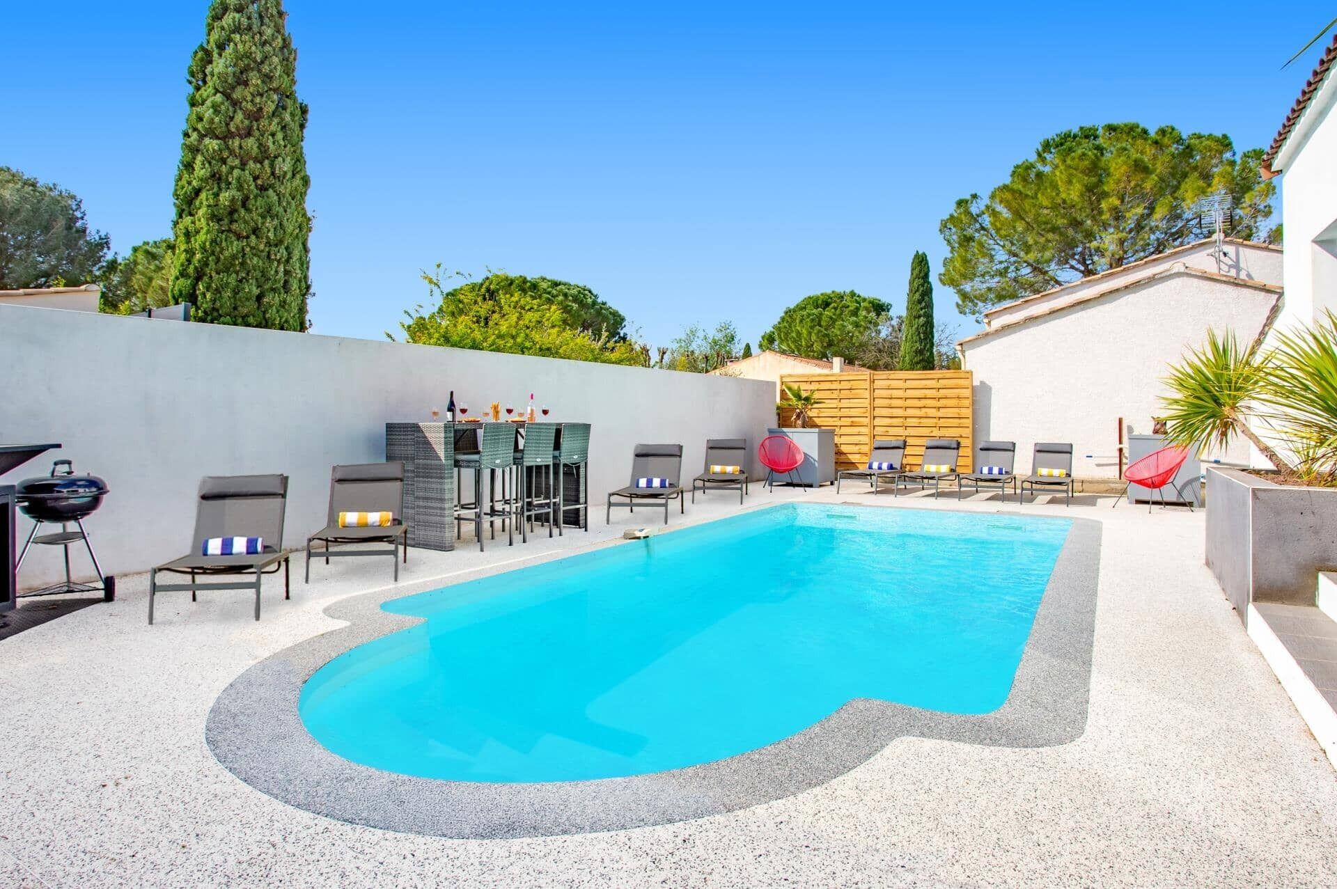 A swimming pool with lounge chairs and a barbecue grill.