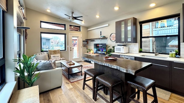 A modern kitchen with a central island, dark cabinetry, and a ceiling fan. - Cozy 2 Bedroom by Teton Pass (Victor)