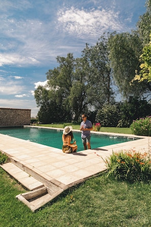 Una piscina al aire libre de temporada, sombrillas, tumbonas