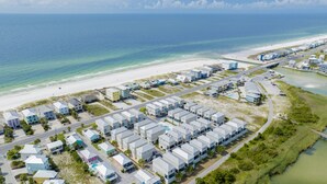 Vista aérea de una zona residencial costera con playa, una carretera y un pequeño cuerpo de agua.
