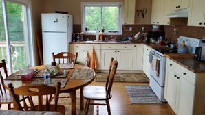 Una cocina con armarios de madera, un refrigerador, una estufa y una mesa de comedor con sillas.