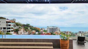 A rooftop terrace with a view of a coastal cityscape, including buildings and the sea. - Beautiful new Studio in Puerto Vallarta with roof top pool and ocean view (Puerto Vallarta)