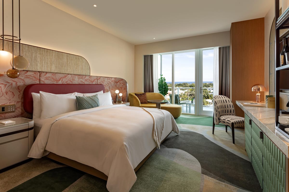 Una habitación de hotel con una cama grande, una zona de estar con vistas y una pequeña kitchenette.
