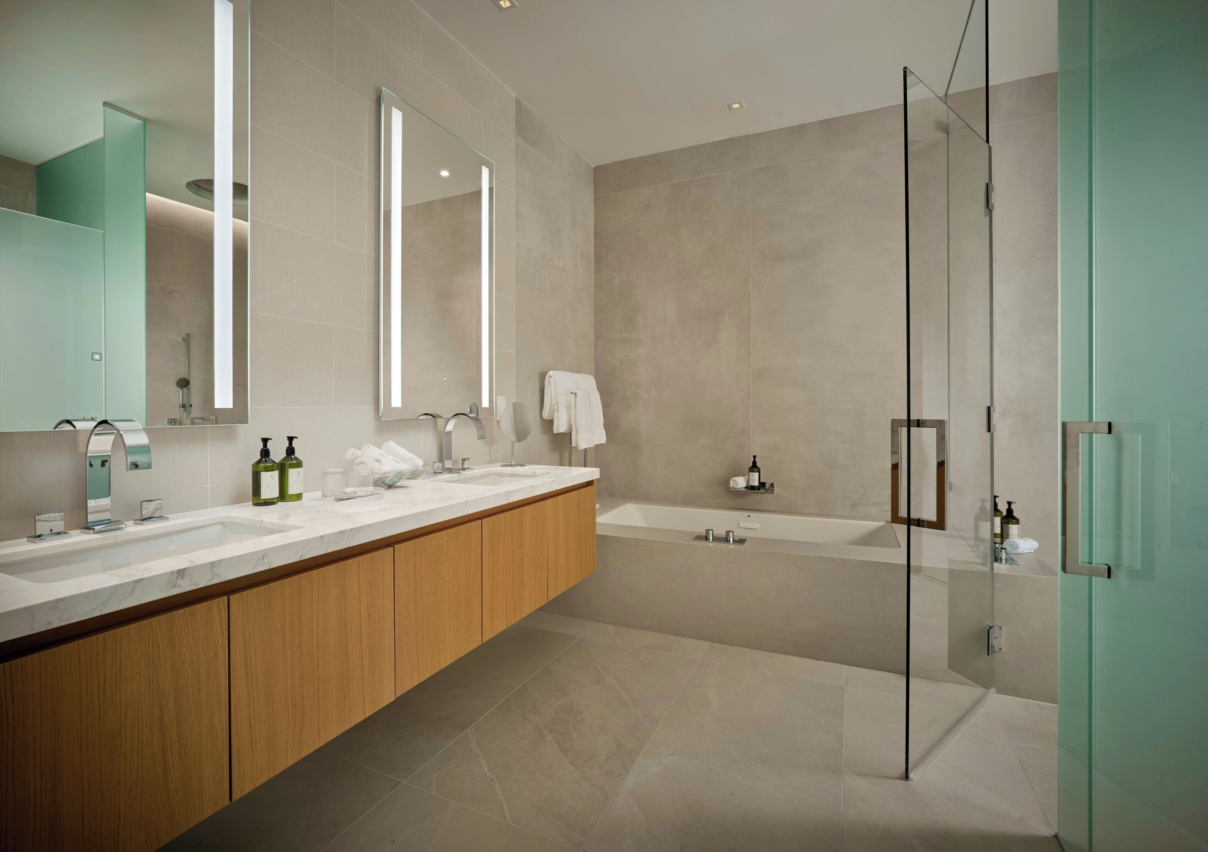A modern bathroom with a glass shower enclosure, a large mirror, and a wooden vanity.