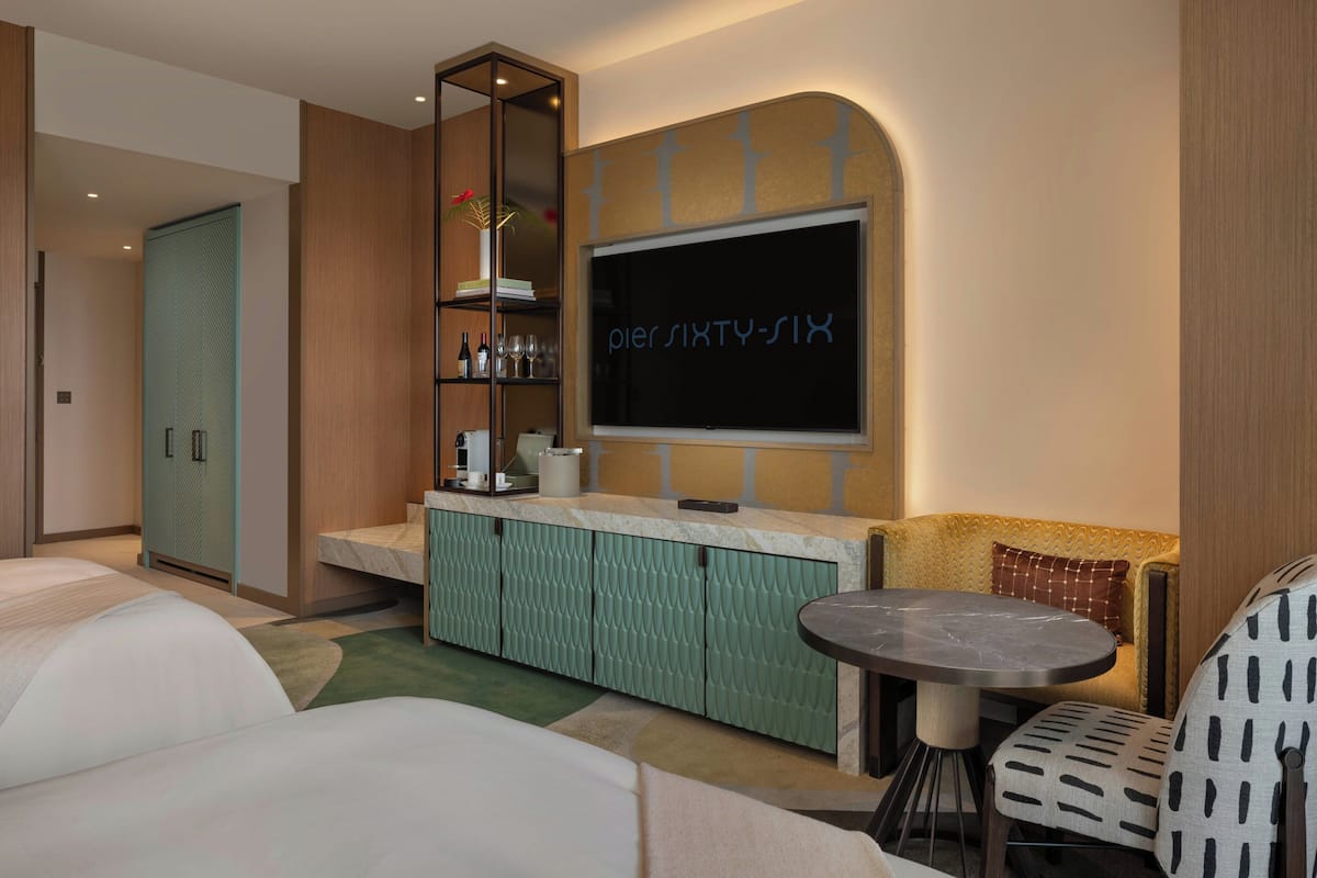 Una habitación de hotel con cama, televisión, minibar, zona de estar y baño.
