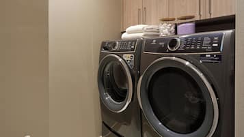 A laundry area with two front-loading washing machines, wooden cabinets, and a woven basket.