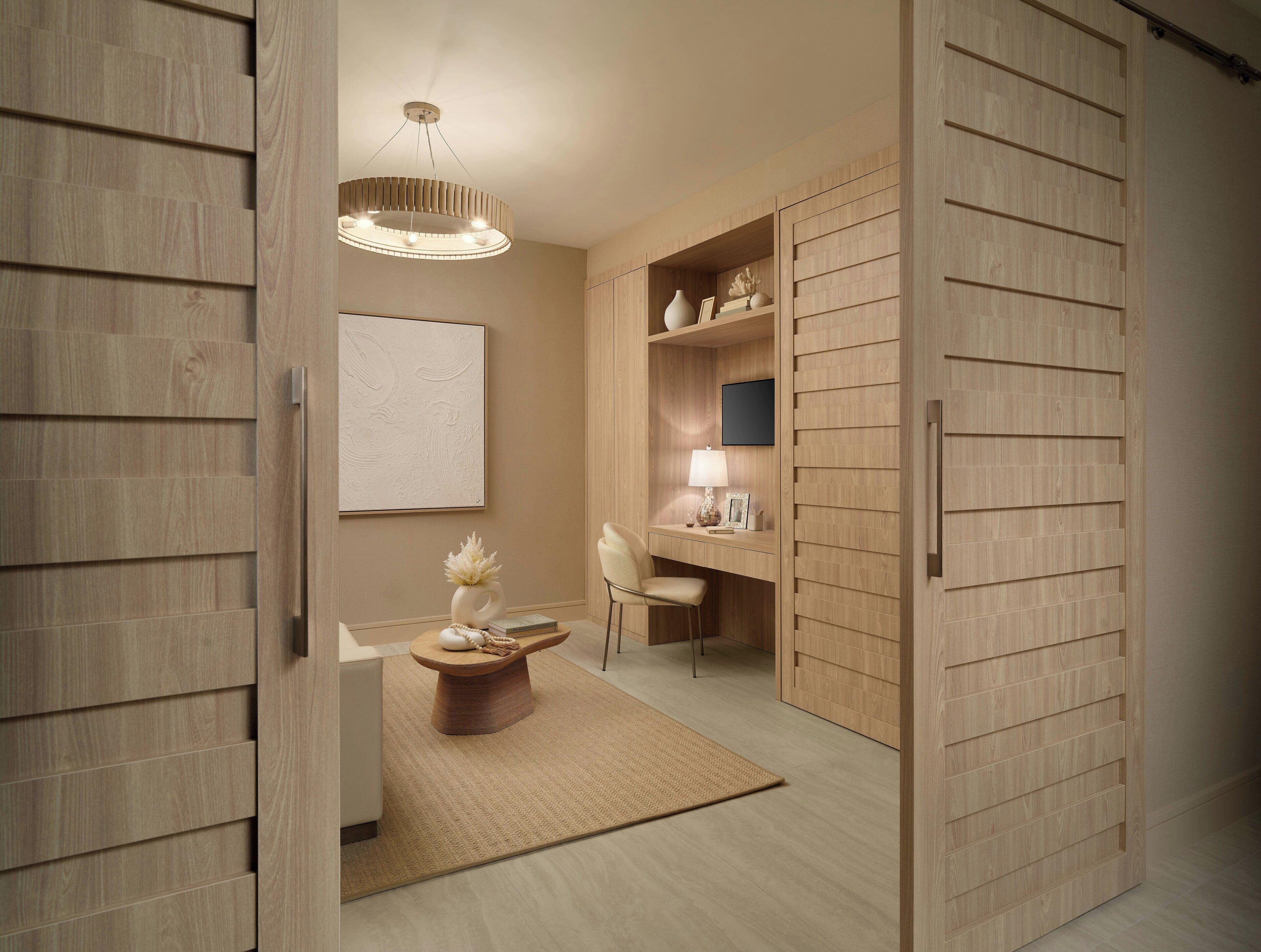 Een modern interieur met een houten vloer, een ronde tafel met een vaas, een stoel, een bureau met een lamp en een aan de muur hangend schilderij.