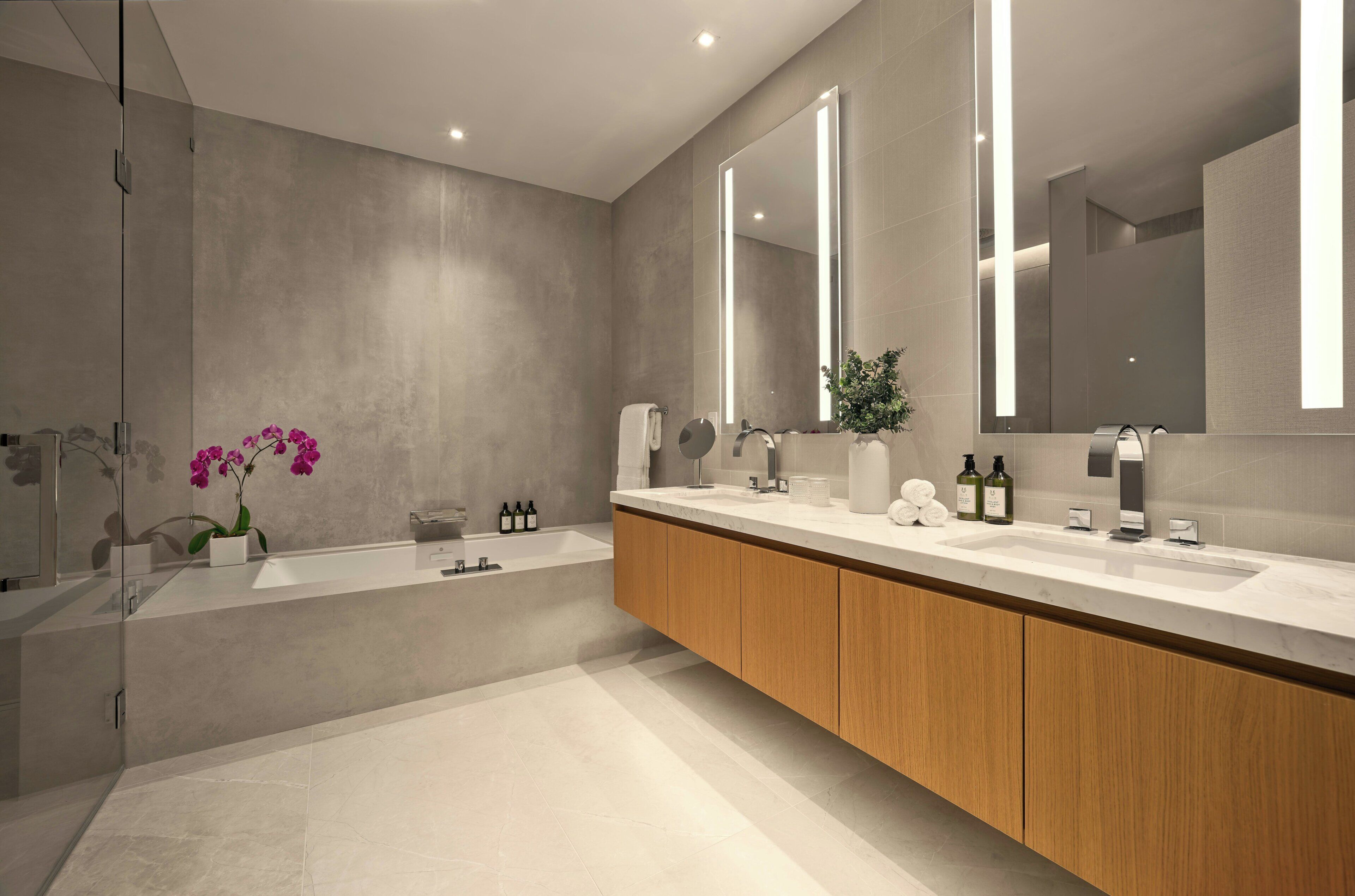 A modern bathroom with a large mirror, a bathtub, and a vanity with a sink.