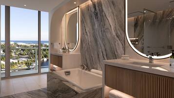 A modern bathroom with a large bathtub, marble walls, and a view of the city.