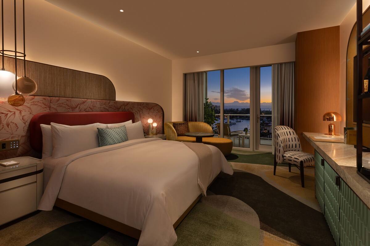 Habitación de hotel con una cama grande, un escritorio, una silla y vistas a la ciudad.