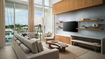 A modern living room with a sofa, coffee table, TV, and wooden shelves.